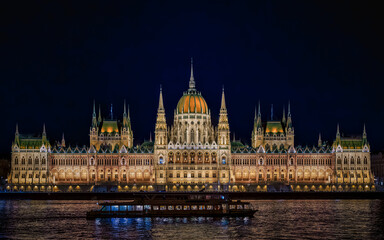 illuminated Hungarian Parliament Building during the blue hour, with a boat cruising on the Danube River