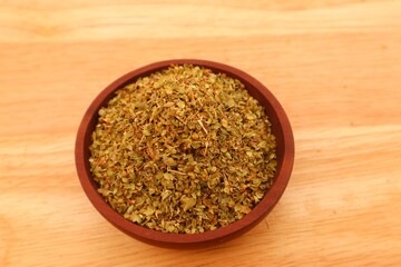 Dried oregano leaves or Origanum vulgare L. In a wooden bowl, close up view.