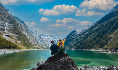 Travelers couple team look on the mountain landscape. Travel and active life concept as Adventure travel in the mountains region in lake marian fiordland national park.