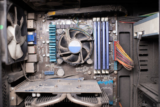 Dusty computer interior showing the motherboard, CPU fan, RAM sticks, and power cables, emphasizing disrepair and poor maintenance