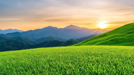 Fototapeta premium Grassy field landscape with mountains in the background under a clear blue sky