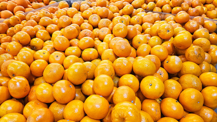 A vibrant, overflowing pile of ripe Mandarin oranges, showcasing their rich, juicy color and texture. Perfect for backgrounds, textures, or food-related projects.