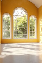 A dance studio with yellow walls and large windows. Light is coming in from the windows, and the floor is painted white. 