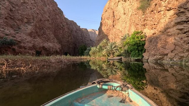 A boat sails down a river in Oman on a calm morning. Wadi Shab in Oman. Wad Shab is iconic tourist spot in Oman