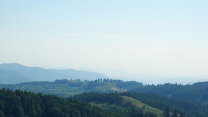 Naklejka premium Serene Mountain Landscape with Rolling Hills and Lush Forests under a Hazy Sky