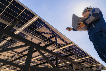 Naklejka premium Engineer in safety vest and helmet pointing towards a solar powered carport, illustrating eco-friendly innovation in parking infrastructure. Solar panels provide shade and sustainable energy.
