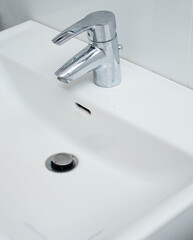 Close up of a bathroom faucet with limescale stains and dirty sink