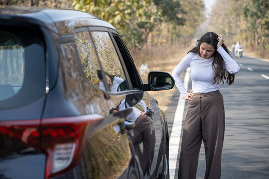 A frustrated girl near her damaged or punctured car