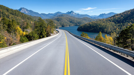 Scenic highway winding through mountains and lake under clear blue sky