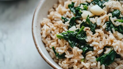 Close-up of a bowl of brown rice with saut&eacute;ed spinach and garlic on a minimalist white plate, highlighting the healthy and simple nature of the meal. Ideal for health-conscious recipes and food blogs.