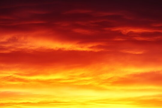 A vibrant sunset casts a fiery gradient across the sky, blending rich orange and deep red colors. This captivating display creates a breathtaking view as evening approaches, enhancing the landscape - Powered by Adobe