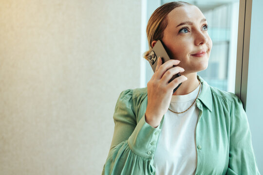 Woman smiling while talking on smartphone by office window