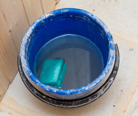 A blue bucket with a sponge in it is filled with water