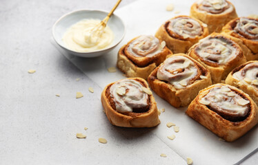 Freshly baked cinnamon rolls topped with cream cheese frosting and almond slivers