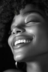 Close-up black-and-white portrait of a young woman laughing, with a happy, smiling expression. 