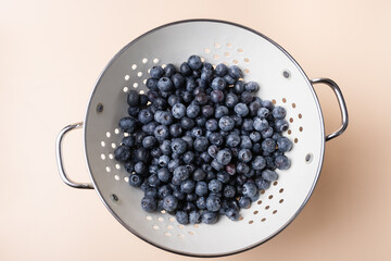 Fresh blueberries in a metal strainer on a light background. Concept of healthy eating, food and freshness