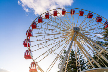 Red and white Ferris Wheel in a park on a sunny summer day with a clear blue sky