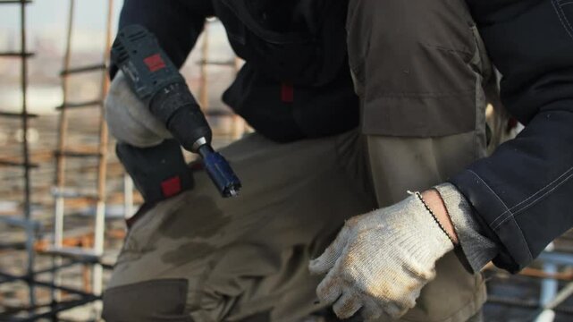 Worker drilling into an electrical junction box on a construction site