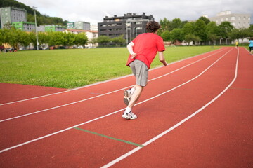 Caucasian young male runner sprinting on running track