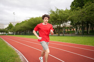 Obraz premium Young man running along a professional running track outdoors