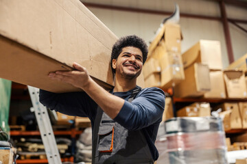 Smiling interracial warehouse worker preparing order and carrying cardboard box in storage.