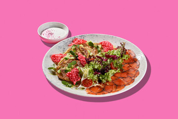 A vibrant and colorful plate of Ukrainian-style deruny, served with smoked salmon, red caviar, and fresh herbs