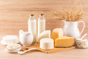 Traditional dairy products for the Jewish holiday of Shavuot on a wooden background. Front view. a large jug with ears of bread.