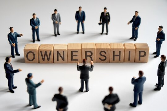 Businesspeople surrounding wooden blocks spelling 'Ownership', signifying shared responsibility and collaborative enterprise.