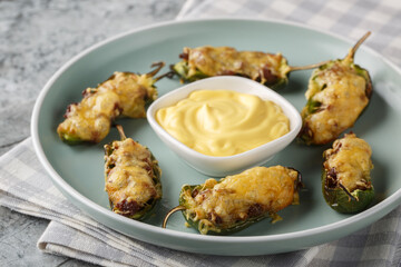 Jalapeno Poppers are filled with cream cheese and a spicy ground beef mixture and baked closeup on the plate on the table. Horizontal