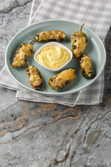 Baked jalapeno peppers with ground beef and cheese served with sauce close-up in a plate on the table. Vertical