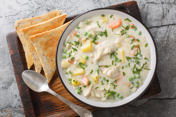 Tasty chicken pot pie soup tastes just like the pie without having to make a crust closeup on the wooden board on the table. Horizontal top view from above