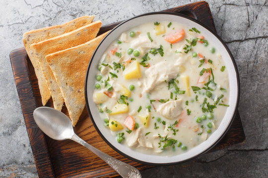 Tasty chicken pot pie soup tastes just like the pie without having to make a crust closeup on the wooden board on the table. Horizontal top view from above