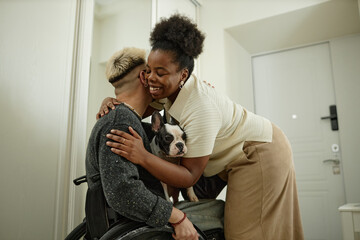 Side view of African American woman brimming with happiness giving gentle embrace to welcoming...