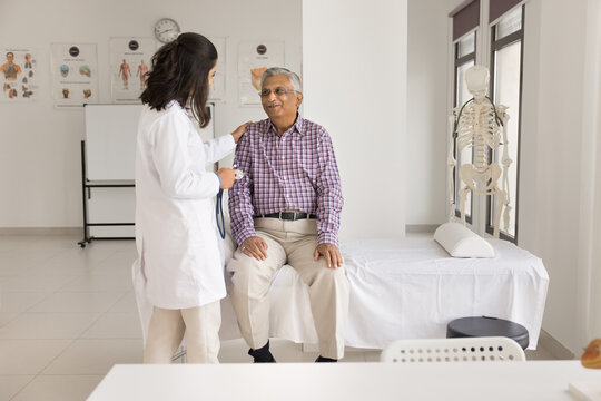Your heart is healthy. Happy smiling doctor put hand on shoulder of aged patient pensioner sitting on medical couch after cardio checkup glad to inform about good health state low cardiovascular risks