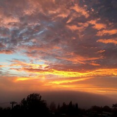 Obraz premium Stunning Sunset Over Calm Landscape with Colorful Clouds