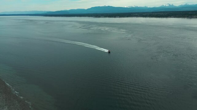 aerial shot over discovery passage between campbell river and quadra island revealing the mount washington in the background and a boat sailing, vancouver island, british columbia, canada