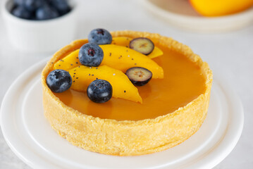 Mango pie with fresh blueberry and chia seeds in a plate. Sugar, sugar substitutes, lactose and gluten free. Vegan tart.