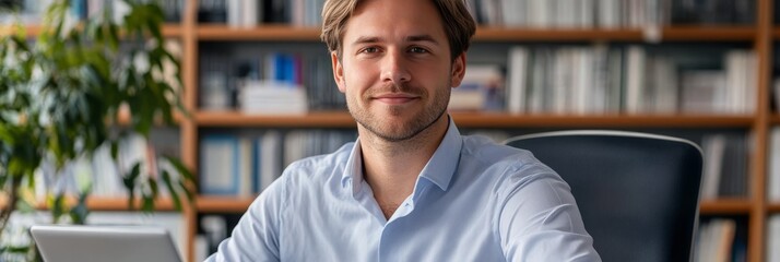 Portrait Of A Happy Young Professional Man At His Office Desk, Working On Laptop With A Smile.