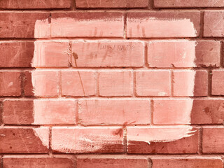 Obraz premium Brick wall with fresh paint applied in rectangular patch creating a contrast against the textured background