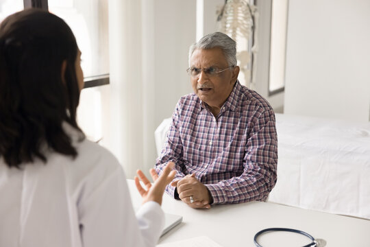 Professional doctor medic worker therapist hold conversation with scared nervous shocked senior adult patient calm down depressed stressed aged visitor comfort old person suffering from hypochondria