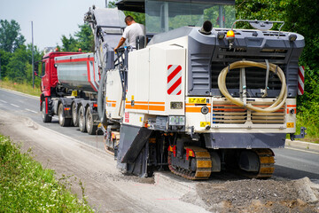 An asphalt milling machine operating on a highway construction site, close up.