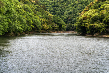 Green lush foliage landscape in Arashiyama district of Kyoto, Japan. Beautiful view with Rankyo Gorge along Katsura river.