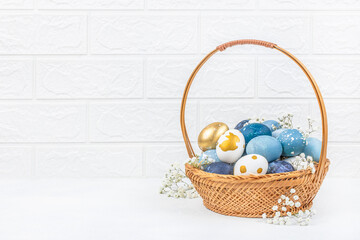 wooden basket with colorful easter eggs on white background surrounded by gypsophila flowers. copy space