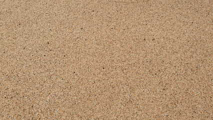Stones and sand in the summer day. Yellow sand on the beach near a sea.