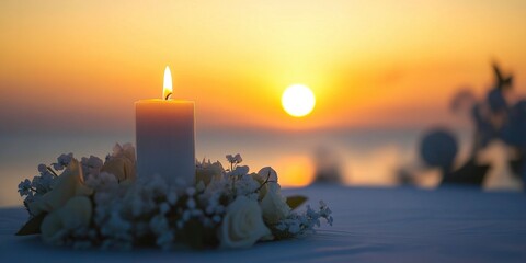 A candle is lit on the table, surrounded by beautiful flowers, sunset sky and water on blur background