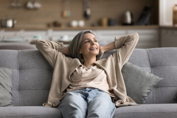 Pleasure of doing nothing. Serene mindful older adult woman relax sitting on comfortable couch at...