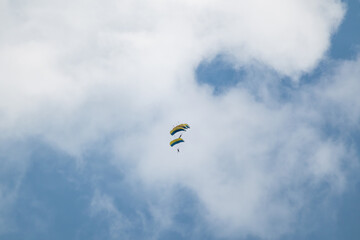 Skydiver parachutists performing aerobatics with yellow-blue ukrainian colored parachutes in cloudy sky