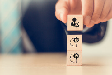 Mindset and skillset development concept. Wooden blocks with icons representing mindset and skillset. A hand stacks the blocks, symbolizing the building of skills, knowledge, growth mindset for leader