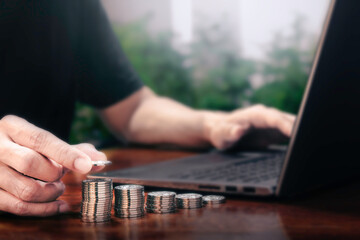Man making stack of coin and working with laptop. invest save finance, saving money, investment concept.