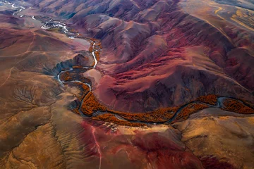 Fototapete Rund Tiefbraun Vivid aerial shot of mountainous valley showcasing red and orange hues, flowing river, autumn foliage, unique erosion patterns, scenic landscape resembling Martian environment rugged Altai Mountains  © Anton Gvozdikov